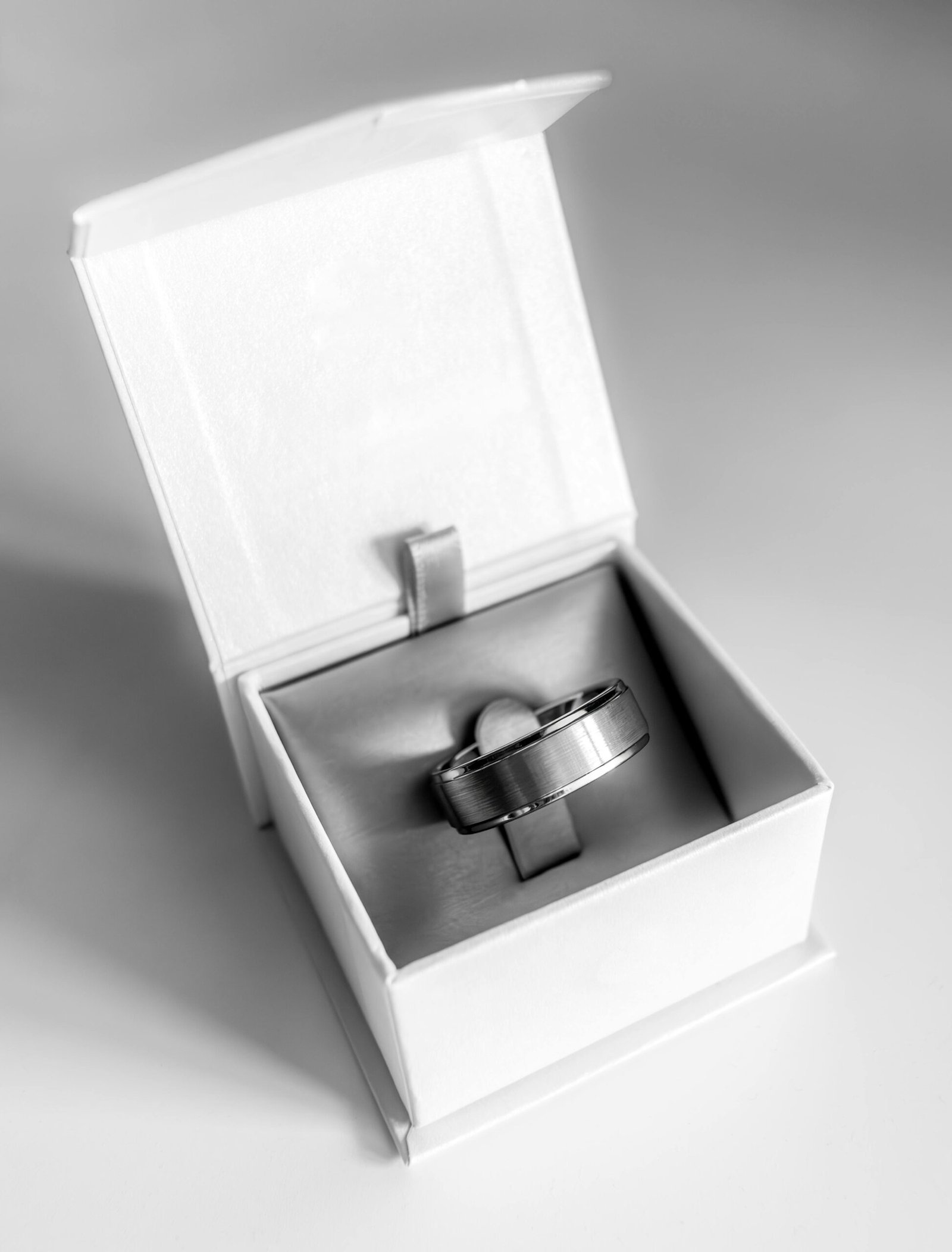 Close-up of a silver wedding band displayed inside an open box.
