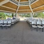 Rows of ceremony seating set up under a lakeside pavilion