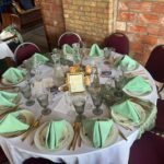 Elegant table setting with vintage china, gold flatware, and sage green napkins